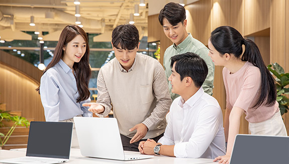 남녀 5명이 모여서 노트북을 보며 이야기하는 모습